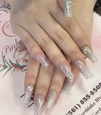 Glitter coffin nails with crystal accents over the salon's printed pink card